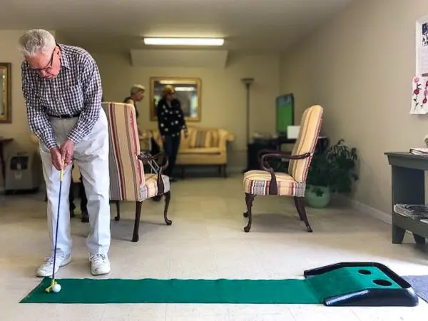 Senior man playing indoor mini-golf at Old Glory Days Adult Day Care in Sandy Hook, CT.