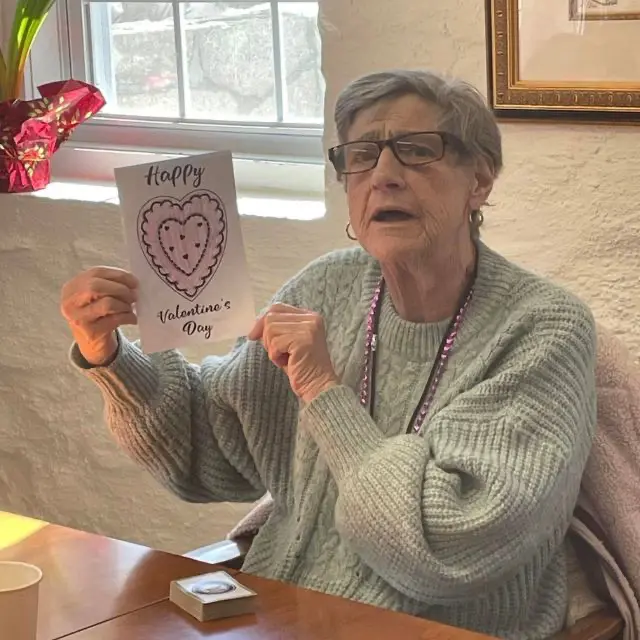 Senior woman at Old Glory Days holding a handmade Valentine’s Day card at Adult Day Care near Newtown CT